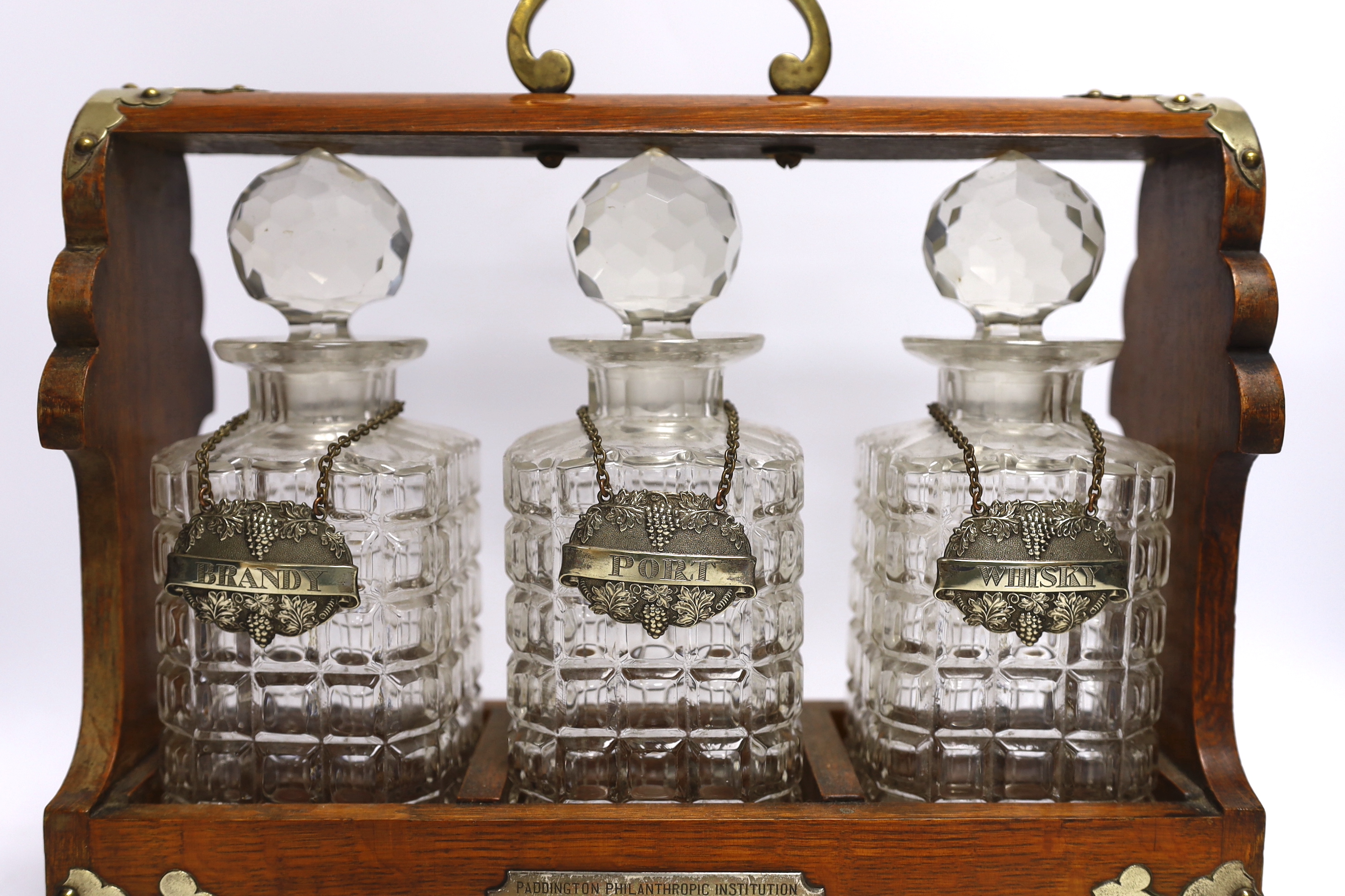 A three bottle tantalus with silver mounts and engraved Masonic presentation, 36cm wide
